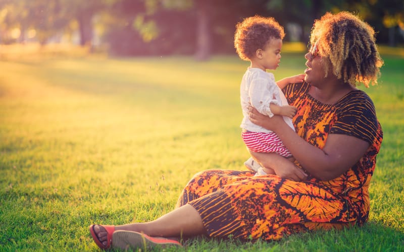 A Black woman holds her grandchild at the park