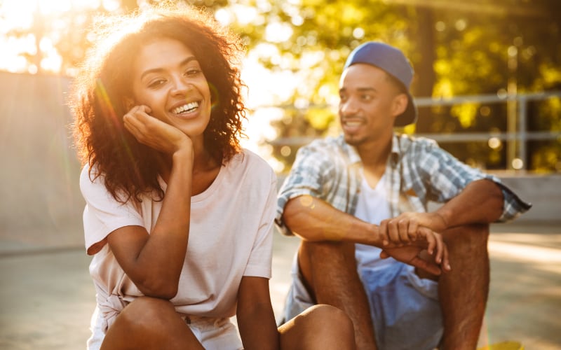 A Black teen girl and boy sit together outside